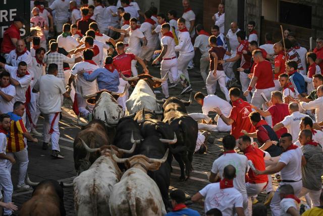 Participants run ahead of bulls from the Victoriano del Rio bull ranch during the third running of the bulls of the San Fermin festival in Pamplona, northern Spain, on July 9, 2026. Thousands of people every year attend the week-long festival and its famous 'encierros', or running of the bulls, in which six bulls are released at 8:00 a.m. evey day to run from their corral to the bullring through the narrow streets of the old town over an 850 meters (yards) course while runners ahead of them try to stay close to the bulls without falling over or being gored. (Photo by JORGE GUERRERO / AFP)
