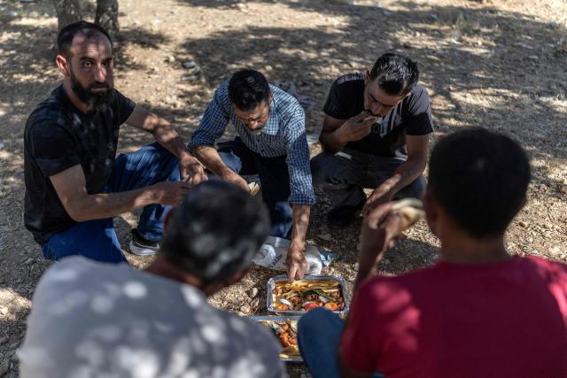 Relatives and family members of Palestinian prisoners, eat in the shade while waiting for their release from Israeli prison at the checkpoint on the outskirts of Israeli occupied West Bank city of Ramallah on July 8, 2026. The number of Palestinian detainees in Israeli prisons stands at around 9,500, according to figures released in June by the Palestinian Prisoners Club, the main rights group for Palestinian prisoners. Since the start of the Gaza war in October 2023, violence has escalated in the Israeli-occupied West Bank. (Photo by ilia YEFIMOVICH / AFP)