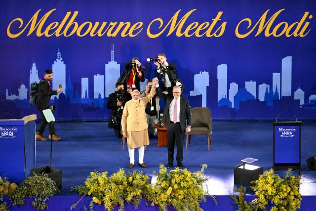 Australia’s Prime Minister Anthony Albanese (R) and Indian Prime Minister Narendra Modi hold hands on stage during a community event at Docklands Stadium in Melbourne on July 9, 2026. (Photo by WILLIAM WEST / AFP)
