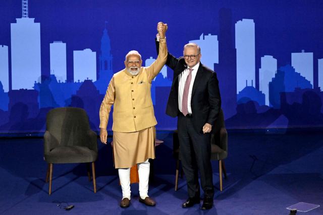 Australia’s Prime Minister Anthony Albanese (R) and Indian Prime Minister Narendra Modi hold hands on stage during a community event at Docklands Stadium in Melbourne on July 9, 2026. (Photo by WILLIAM WEST / AFP)