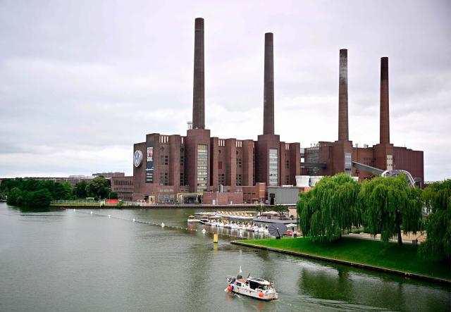 A general view taken on July 9, 2026 shows a boat passing on the Mittelland Canal in front of the Wolfsburg Volkswagen (VW) Plant in Wolfsburg, Germany, prior to a planned rally of VW employees called by German trade union IG Metall to protest against restructuring and mass job cut plans at the VW headquarters in Wolfsburg, Germany. IG Metall is organising protests by VW workers outside plants across the country on July 9, when the carmaker's bosses will present the restructuring plans to the supervisory board. Europe's largest carmaker has come under intense pressure from US tariffs, slimmer profit margins from electric cars and above all intense competition in China, the world's largest auto market. VW, whose 10 brands range from mass-market Seats to premium Porsches, is already in the process of axing 50,000 jobs in Germany by 2030, including 35,000 at its namesake marque. (Photo by Tobias SCHWARZ / AFP)