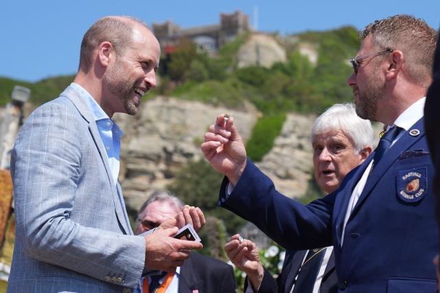 Britain's Prince William, Prince of Wales (L), receives a silver winkle as he meets with members from the charity organisation the Winkle Club in the Old Town, during his visit to Hastings, south-east England on July 9, 2026, to highlight the town's fishing community and the vital work of local youth-led and community-driven organisations. (Photo by Gareth Fuller / POOL / AFP)