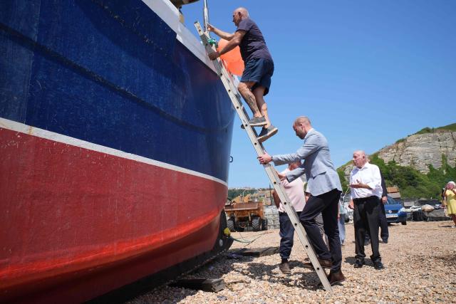 Britain's Prince William, Prince of Wales (bottom R), climbs a ladder to board a fishing boat in the Old Town, during his visit to Hastings, south-east England on July 9, 2026, to highlight the town's fishing community and the vital work of local youth-led and community-driven organisations. (Photo by Gareth Fuller / POOL / AFP)