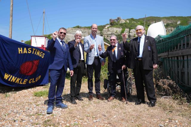 Britain's Prince William, Prince of Wales (C), receives a silver winkle as he meets with members from the charity organisation the Winkle Club in the Old Town, during his visit to Hastings, south-east England on July 9, 2026, to highlight the town's fishing community and the vital work of local youth-led and community-driven organisations. (Photo by Gareth Fuller / POOL / AFP)