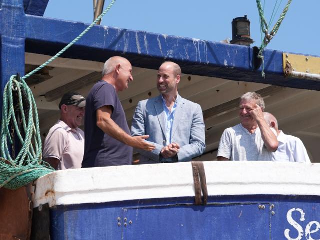 Britain's Prince William, Prince of Wales (C), meets fishermen while on a fishing boat in the Old Town, during his visit to Hastings, south-east England on July 9, 2026, to highlight the town's fishing community and the vital work of local youth-led and community-driven organisations. (Photo by Gareth Fuller / POOL / AFP)
