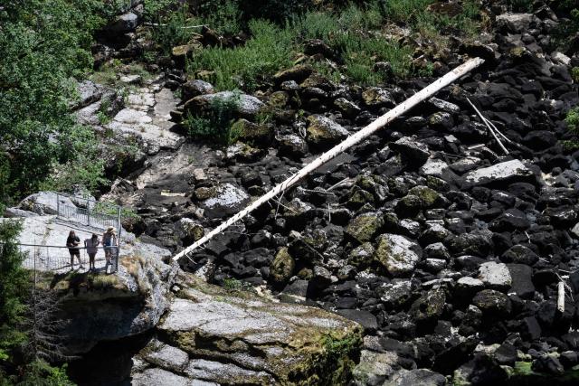 Hikers look at the dry riverbed of the Doubs river at the 'saut du doubs' waterfall on July 9, 2026, in Villers-le-Lac, eastern France. (Photo by SEBASTIEN BOZON / AFP)