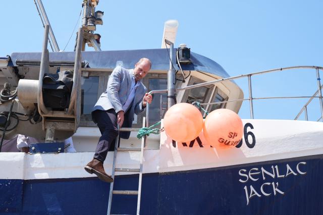 Britain's Prince William, Prince of Wales, climbs down a ladder as he leaves a fishing boat in the Old Town, during his visit to Hastings, south-east England on July 9, 2026, to highlight the town's fishing community and the vital work of local youth-led and community-driven organisations. (Photo by Gareth Fuller / POOL / AFP)