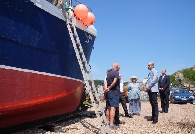 Britain's Prince William, Prince of Wales (2nd R) meets fishermen in the Old Town, during his visit to Hastings, south-east England on July 9, 2026, to highlight the town's fishing community and the vital work of local youth-led and community-driven organisations. (Photo by Gareth Fuller / POOL / AFP)
