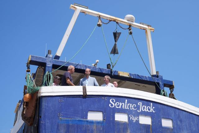 Britain's Prince William, Prince of Wales (C) meets fishermen while on a fishing boat in the Old Town, during his visit to Hastings, south-east England on July 9, 2026, to highlight the town's fishing community and the vital work of local youth-led and community-driven organisations. (Photo by Gareth Fuller / POOL / AFP)