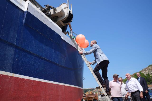 Britain's Prince William, Prince of Wales (C), climbs a ladder to board a fishing boat in the Old Town, during his visit to Hastings, south-east England on July 9, 2026, to highlight the town's fishing community and the vital work of local youth-led and community-driven organisations. (Photo by Gareth Fuller / POOL / AFP)