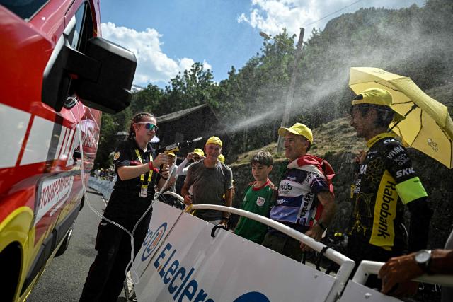 A firefighter spray water on spectators at the finish line amid a heatwave, during the 6th stage of the 113th edition of the Tour de France cycling race, 186 km between Pau and Gavarnie-Gèdre in the French Pyrenees, on July 9, 2026. (Photo by Loic VENANCE / AFP)