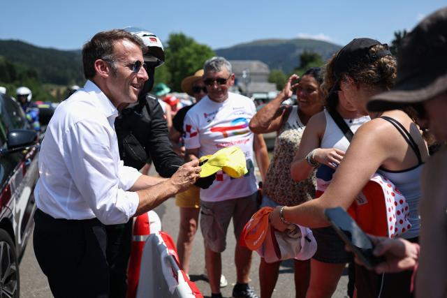 France's President Emmanuel Macron signs promotional hats handed to spectators by sponsors on the sidelines of the 6th stage of the 113th edition of the Tour de France cycling race, 186,2 km between Pau and Gavarnie-Gèdre in the French Pyrenees, on July 9, 2026. (Photo by Anne-Christine POUJOULAT / AFP)