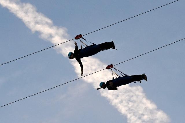 A couple rides the Mekong Zipline, which connects Diamond island (Koh Pich) to Norea island across the Bassac river, in Phnom Penh on July 9, 2026. (Photo by TANG CHHIN Sothy / AFP)