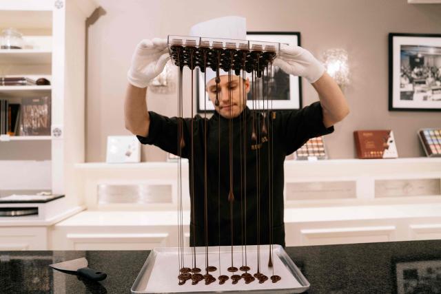 A chocolate maker works at a Neuhaus chocolatier shop of the Koninginnegalerij - Galerie de la Reine, in the city center of Brussels on July 9, 2026. (Photo by Marius BURGELMANS / Belga / AFP) / Belgium OUT