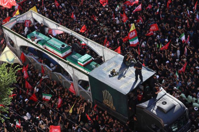 Crowds of mourners surround the convoy carrying the coffins of Iran's slain supreme leader Ali Khamenei and members of his family during a funeral procession, before he is buried at the Shrine of Imam Reza, Iran's most revered place of worship, in Mashhad on July 9, 2026. Braving sweltering heat and calling for revenge, Iranians loyal to the Islamic republic massed on July 9 for the burial of slain supreme leader Ali Khamenei in his hometown of Mashhad. (Photo by ATTA KENARE / AFP) / 