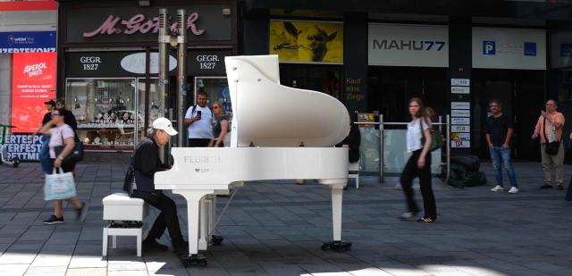 Music professor of Fukuoka University Fukuda Nobumitsu who lives in Vienna, plays a piano free to play for everybody at Mariahilfer street in Vienna, Austria, on July 09, 2026. (Photo by Joe KLAMAR / AFP)