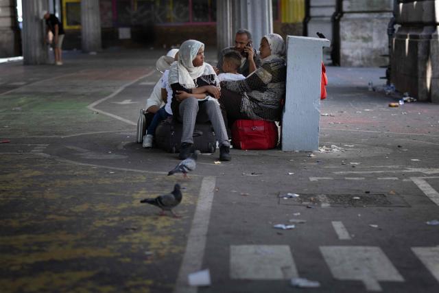 A migrant family sit next to their belongings at a campsite located beneath Line 2 of the elevated metro at La Chapelle station in Paris on July 9, 2026. (Photo by JOEL SAGET / AFP)