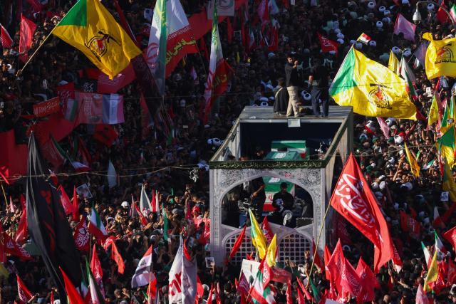 Crowds of mourners surround the convoy carrying the coffins of Iran's slain supreme leader Ali Khamenei and members of his family during a funeral procession, before he is buried at the Shrine of Imam Reza, Iran's most revered place of worship, in Mashhad on July 9, 2026. Braving sweltering heat and calling for revenge, Iranians loyal to the Islamic republic massed on July 9 for the burial of slain supreme leader Ali Khamenei in his hometown of Mashhad. (Photo by ATTA KENARE / AFP) / 