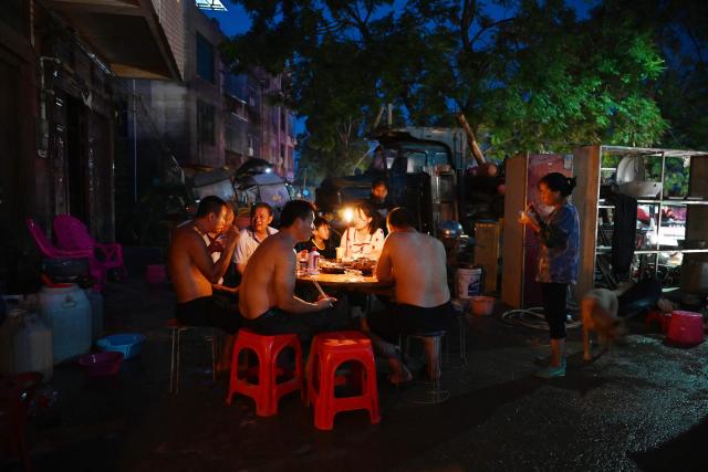 Residents eat dinner by candlelight outside a house in Gantang after electricity was knocked out by floodwaters from a collapsed reservoir in China’s southwest Guangxi region on July 9, 2026. The death toll from devastating floods in southern China's Guangxi region rose to 39 on July 9, with nine people still missing, state media reported, as residents went about cleaning up. (Photo by GREG BAKER / AFP)