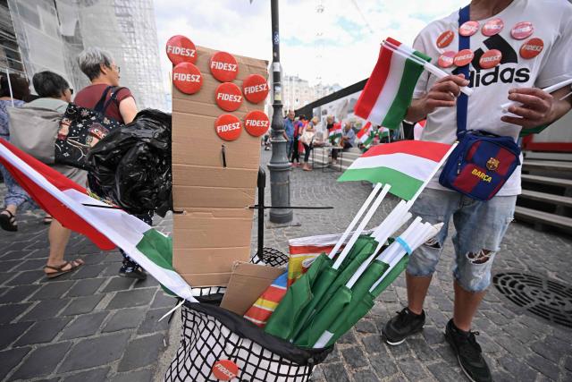 A street vendor offers FIDESZ badges and Hungarian tricolors to those arriving at a demonstration of supporters of the former government party-coalition Fidesz–KDNP (Fidesz – Hungarian Civic Alliance and the Christian Democratic People's Party (KDNP) with the motto 'Put an End to Arbitrariness!' in Budapest on July 09, 2026. According to the organisers, the aim of the demonstration is to protest against the 17th Amendment to the Fundamental Law initiated by the Tisza government, which would affect several public offices, including the position of President of the Republic Tamas Sulyok. (Photo by Attila KISBENEDEK / AFP)