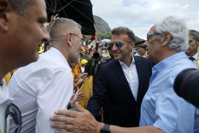 France's President Emmanuel Macron shakes hands with spectators at the finish are of the 6th stage of the 113th edition of the Tour de France cycling race, 186 km between Pau and Gavarnie-Gèdre in the French Pyrenees, on July 9, 2026. (Photo by Guillaume HORCAJUELO / POOL / AFP)
