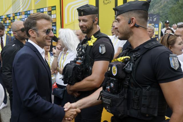 France's President Emmanuel Macron speaks with a gendarme at the finish are of the 6th stage of the 113th edition of the Tour de France cycling race, 186 km between Pau and Gavarnie-Gèdre in the French Pyrenees, on July 9, 2026. (Photo by Guillaume HORCAJUELO / POOL / AFP)