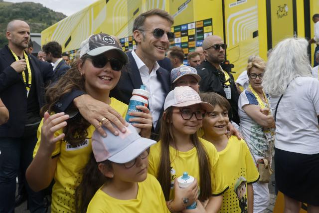 France's President Emmanuel Macron poses for photographs with children at the finish are of the 6th stage of the 113th edition of the Tour de France cycling race, 186 km between Pau and Gavarnie-Gèdre in the French Pyrenees, on July 9, 2026. (Photo by Guillaume HORCAJUELO / POOL / AFP)