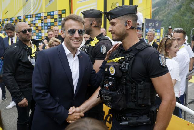 France's President Emmanuel Macron speaks with a gendarme at the finish are of the 6th stage of the 113th edition of the Tour de France cycling race, 186 km between Pau and Gavarnie-Gèdre in the French Pyrenees, on July 9, 2026. (Photo by Guillaume HORCAJUELO / POOL / AFP)