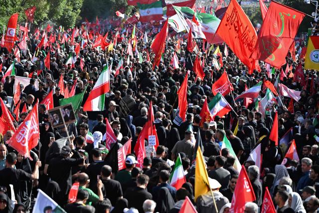 Crowds of mourners gather on a street around a portrait of Iran's supreme leader Mojtaba Khamenei ahead of the funeral procession of Iran's slain supreme leader Ali Khamenei and members of his family, before he is buried at the Shrine of Imam Reza, Iran's most revered place of worship, in Mashhad on July 9, 2026. Calling for revenge and rejecting any compromise with the West, Iranians loyal to the Islamic republic braved sweltering heat on July 9 to mass for the burial of supreme leader Ali Khamenei in his hometown of Mashhad. (Photo by Wakil Kohsar / AFP) / 