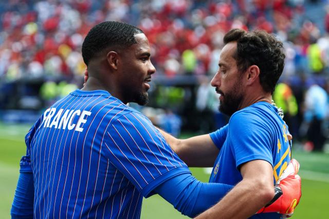 France's goalkeeper #16 Mike Maignan (L) and Brazilian football player Nene (R) hug ahead of the 2026 World Cup football tournament quarter-final match between France and Morocco at Boston Stadium in Foxborough on July 9, 2026.  (Photo by FRANCK FIFE / AFP)