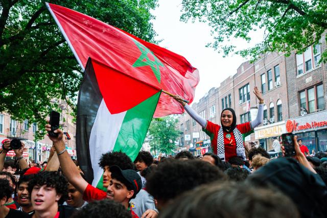 A woman waves a Palestine flag among Moroccan fans celebrating their team participation in the World Cup, despite the 2-0 loss against France in the quarter-final match between France and Morocco in the Little Morocco area in the Queens borough of New York City on July 9, 2026. (Photo by Angelina Katsanis / AFP)