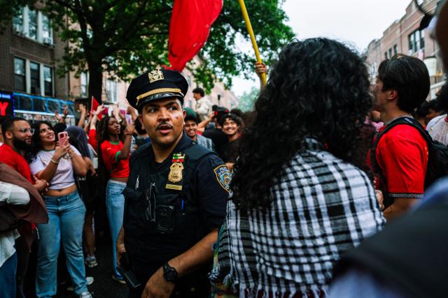 An NYPD officer tries to clear the streets as Moroccan fans celebrate their team participation in the World Cup, despite the 2-0 loss against France in the quarter-final match between France and Morocco, in the Little Morocco area in the Queens borough of New York City on July 9, 2026. (Photo by Angelina Katsanis / AFP)