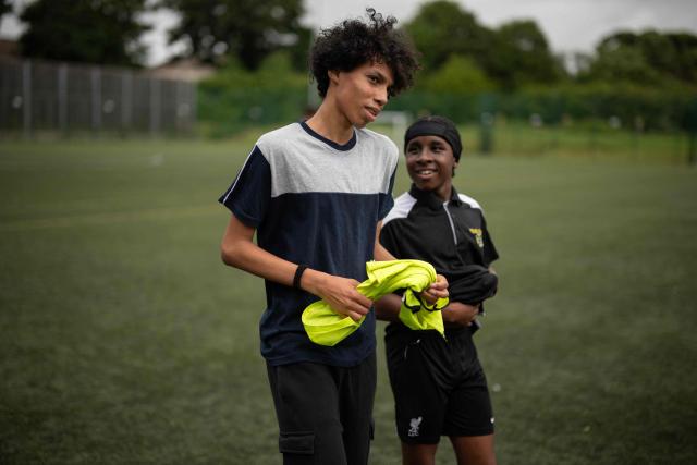 Fabian Myers (L) and Kaziah Cameron (R), year 9 students at Our Lady & St Chad Catholic School, who participate in the 'Football Beyond Borders' programme, depart after playing a football match with fellow FBB students in Wolverhampton, central England on June 12, 2026. FBB (Football Beyond Borders) works with young people from areas of socio-economic disadvantage who are disengaged at school but passionate about football, to help them finish school with the skills and grades to make a successful transition into adulthood. (Photo by Oli SCARFF / AFP) / TO GO WITH AFP STORY BY Alexandra Del PERAL