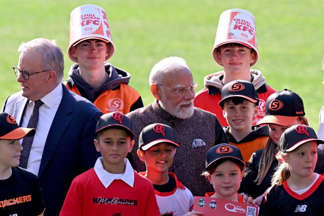 Indian Prime Minister Narendra Modi (C) and Australia’s Prime Minister Anthony Albanese (L) talk with children after posing for a photograph during a visit to the Melbourne Cricket Ground (MCG) on July 10, 2026. (Photo by WILLIAM WEST / AFP)
