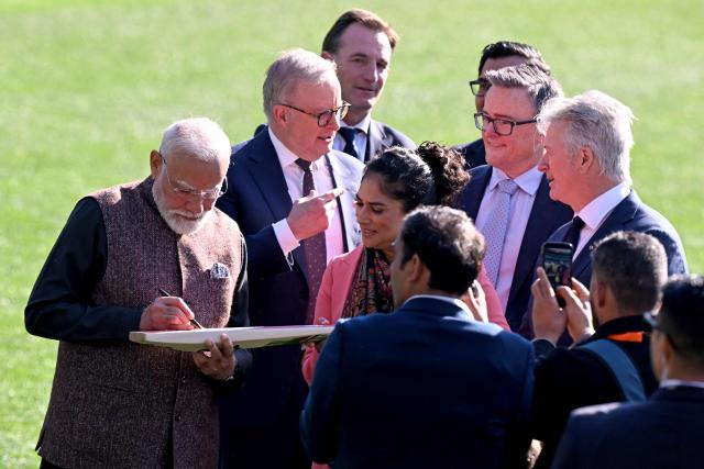 Indian Prime Minister Narendra Modi (L) signs a cricket bat as he stands with Australia’s Prime Minister Anthony Albanese (2nd L), former Australian cricket player Steve Waugh (R) and officials during a visit to the Melbourne Cricket Ground (MCG) on July 10, 2026. (Photo by WILLIAM WEST / AFP)