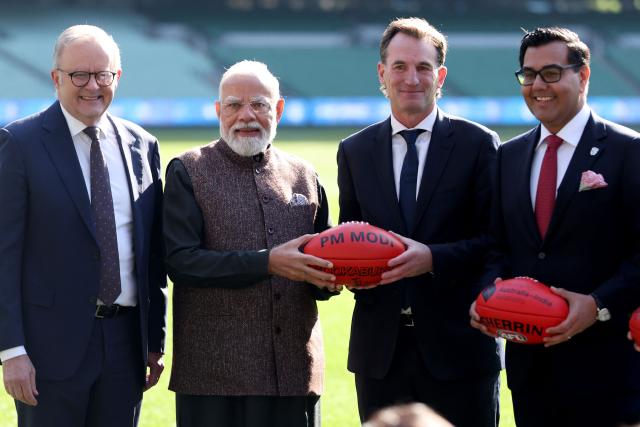 Australia’s Prime Minister Anthony Albanese (L) stands behind Indian Prime Minister Narendra Modi (2nd L) as he is presented with an Australian Rules football bearing his name during a visit to the Melbourne Cricket Ground (MCG) on July 10, 2026. (Photo by MARTIN KEEP / AFP)
