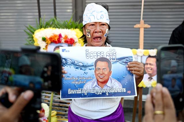 A woman cries while speaking to the media as she holds an image of former prominent Cambodian critic Kem ley during the 10th anniversary of his murder at a gasoline station in Phnom Penh on July 10, 2026. (Photo by TANG CHHIN Sothy / AFP)