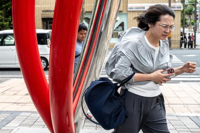 A pedestrian walks against strong winds in Naha, the capital city of Okinawa Prefecture, on July 10, 2026. (Photo by Philip FONG / AFP)