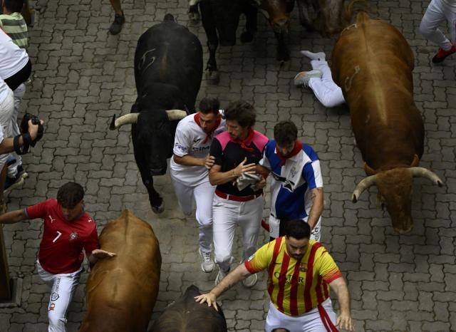Participants run ahead of bulls during the fourth running of the bulls of the San Fermin festival in Pamplona, northern Spain, on July 10, 2026. Thousands of people every year attend the week-long festival and its famous 'encierros', or running of the bulls, in which six bulls are released at 8:00 a.m. evey day to run from their corral to the bullring through the narrow streets of the old town over an 850 meters (yards) course while runners ahead of them try to stay close to the bulls without falling over or being gored. (Photo by ANDER GILLENEA / AFP)