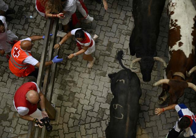 Participants run ahead of bulls during the fourth running of the bulls of the San Fermin festival in Pamplona, northern Spain, on July 10, 2026. Thousands of people every year attend the week-long festival and its famous 'encierros', or running of the bulls, in which six bulls are released at 8:00 a.m. evey day to run from their corral to the bullring through the narrow streets of the old town over an 850 meters (yards) course while runners ahead of them try to stay close to the bulls without falling over or being gored. (Photo by ANDER GILLENEA / AFP)