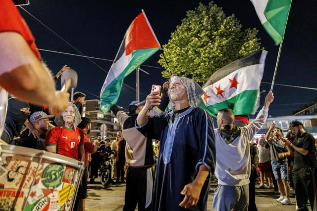 Moroccan football fans react in a street waving flags of Morocco following Morocco's defeat against France in the 2026 World Cup quarter final football match in Amsterdamon July 10, 2026. (Photo by Michel van BERGEN / ANP / AFP) / Netherlands OUT