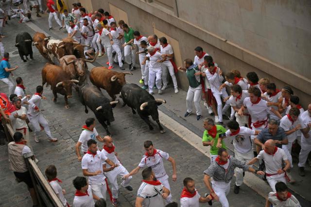 Participants run ahead of bulls during the fourth running of the bulls of the San Fermin festival in Pamplona, northern Spain, on July 10, 2026. Thousands of people every year attend the week-long festival and its famous 'encierros', or running of the bulls, in which six bulls are released at 8:00 a.m. evey day to run from their corral to the bullring through the narrow streets of the old town over an 850 meters (yards) course while runners ahead of them try to stay close to the bulls without falling over or being gored. (Photo by JORGE GUERRERO / AFP)