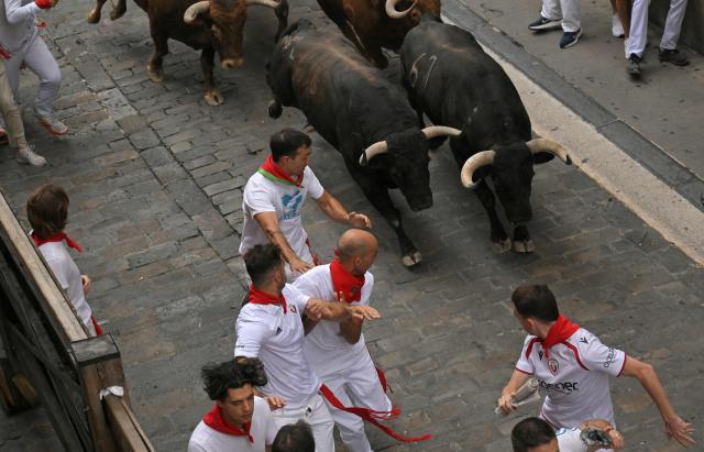 Participants run ahead of bulls during the fourth running of the bulls of the San Fermin festival in Pamplona, northern Spain, on July 10, 2026. Thousands of people every year attend the week-long festival and its famous 'encierros', or running of the bulls, in which six bulls are released at 8:00 a.m. evey day to run from their corral to the bullring through the narrow streets of the old town over an 850 meters (yards) course while runners ahead of them try to stay close to the bulls without falling over or being gored. (Photo by JORGE GUERRERO / AFP)