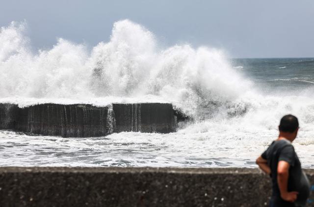 A man looks on as strong waves break along the coast in Yilan on July 10, 2026, as Typhoon Bavi moves toward Northeastern Taiwan. (Photo by I-Hwa Cheng / AFP)
