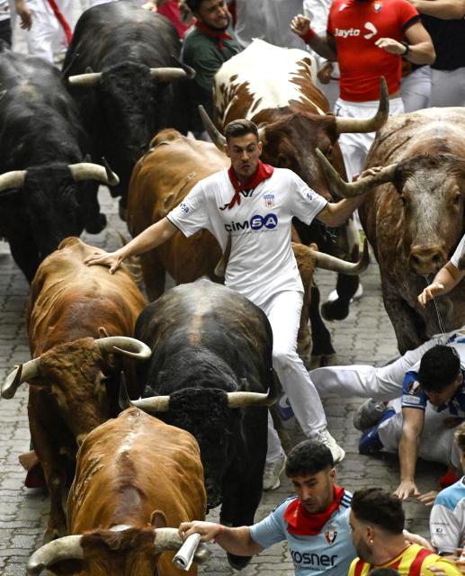 A participant runs with bulls during the fourth running of the bulls of the San Fermin festival in Pamplona, northern Spain, on July 10, 2026. Thousands of people every year attend the week-long festival and its famous 'encierros', or running of the bulls, in which six bulls are released at 8:00 a.m. evey day to run from their corral to the bullring through the narrow streets of the old town over an 850 meters (yards) course while runners ahead of them try to stay close to the bulls without falling over or being gored. (Photo by ANDER GILLENEA / AFP)
