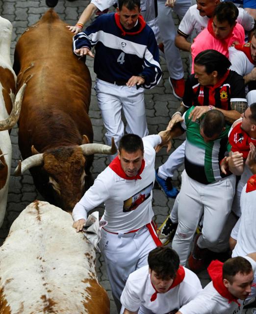 Participants run with bulls during the fourth running of the bulls of the San Fermin festival in Pamplona, northern Spain, on July 10, 2026. Thousands of people every year attend the week-long festival and its famous 'encierros', or running of the bulls, in which six bulls are released at 8:00 a.m. evey day to run from their corral to the bullring through the narrow streets of the old town over an 850 meters (yards) course while runners ahead of them try to stay close to the bulls without falling over or being gored. (Photo by ANDER GILLENEA / AFP)