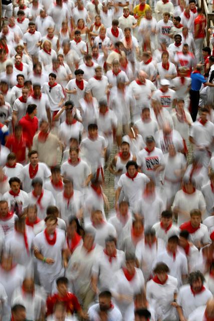 Participants run ahead of bulls during the fourth running of the bulls of the San Fermin festival in Pamplona, northern Spain, on July 10, 2026. Thousands of people every year attend the week-long festival and its famous 'encierros', or running of the bulls, in which six bulls are released at 8:00 a.m. evey day to run from their corral to the bullring through the narrow streets of the old town over an 850 meters (yards) course while runners ahead of them try to stay close to the bulls without falling over or being gored. (Photo by ANDER GILLENEA / AFP)
