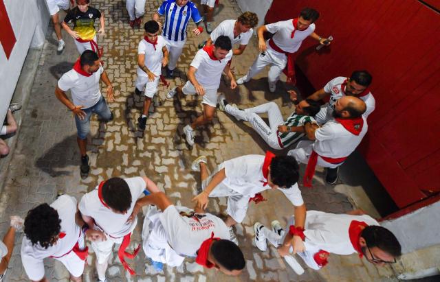 Participants run ahead of bulls during the fourth running of the bulls of the San Fermin festival in Pamplona, northern Spain, on July 10, 2026. Thousands of people every year attend the week-long festival and its famous 'encierros', or running of the bulls, in which six bulls are released at 8:00 a.m. evey day to run from their corral to the bullring through the narrow streets of the old town over an 850 meters (yards) course while runners ahead of them try to stay close to the bulls without falling over or being gored. (Photo by ANDER GILLENEA / AFP)