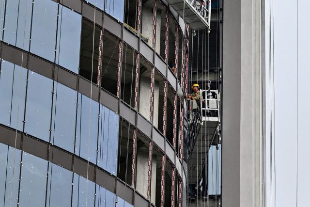 A worker installs panes of glass at a hotel construction site in Hanoi on July 10, 2026. (Photo by Nhac NGUYEN / AFP)