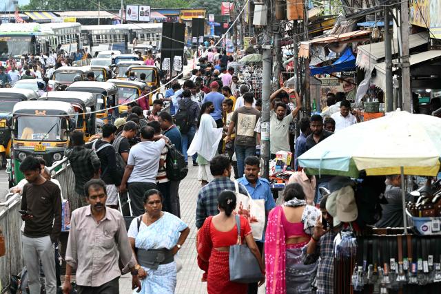 This photograph taken on July 6, 2026 shows pedestrians walking on a footpath along a road in Hyderabad. In India, a pavement can be many things -- hawking site, parking area, garbage dumping space -- but rarely what it is meant to be: a safe unobstructed path to walk on. (Photo by Noah SEELAM / AFP)